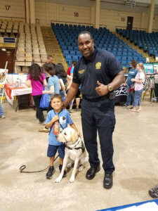 Officer giving a thumbs-up, posing with young child and dog