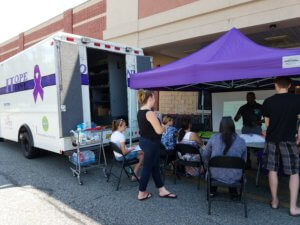 Public attending training under a tent outside Hope One vehicle