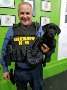 Morris County Sheriff's Office K9 Officer John Granato with an 8-week-old Labrador Retriever that is being donated to the Agency by onPOINT-K9 of Bernards Township. 