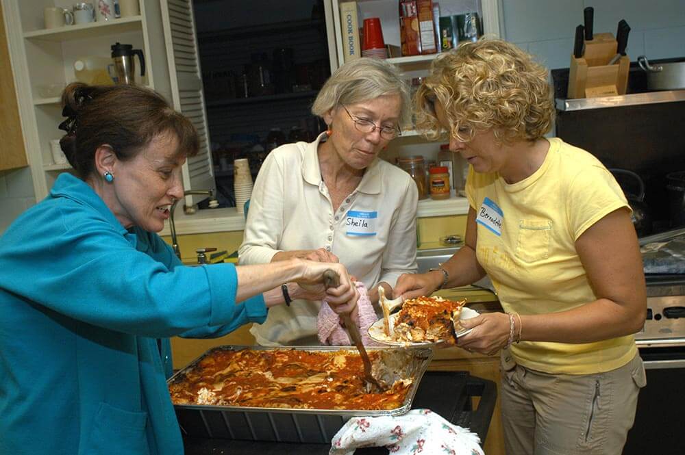 Family Promise volunteers serving lasagna dinner