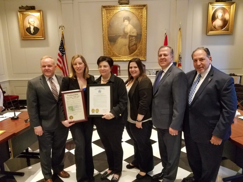 photo of officials standing in Madison town hall, holding proclamation (l/r)Freeholder Doug Cabana, Amanda Holloway, Donna Pasquariello, Michelle Leone, Freeholder Tom Mastrangelo, and Prosecutor Fredric M. Knapp