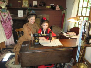 Woman in period dress at a sewing machine with a child