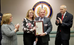 Beth Jacobson poses with Freeholder Director Doug Cabana while freeholders Kathy DeFillippo and John Krickus applaud.