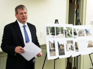 County Engineer Christopher Vitz stands next to easel holding photos of the Hacklebarney Road bridge project