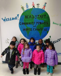 Children in the Morris County Head Start Program pose under a mural of the earth