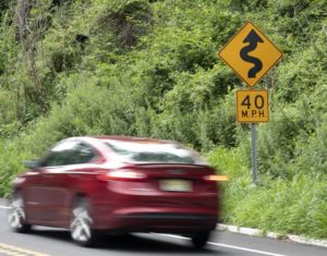 photo shows car passing curved road sign with 40MPH